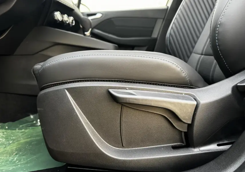 Gros plan sur l'accoudoir avant coulissant gris avec surpiqûres bleues dans l'habitacle de la Renault Clio V hybride.