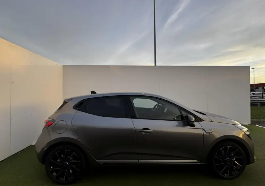 Renault Clio V hybride gris schiste vue de profil côté gauche, jantes alliage noires et vitres teintées.