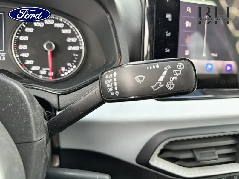 Levier de commande des essuie-glaces en gros plan dans l'habitacle d'une SEAT Arona gris urbain métal, tableau de bord visible.