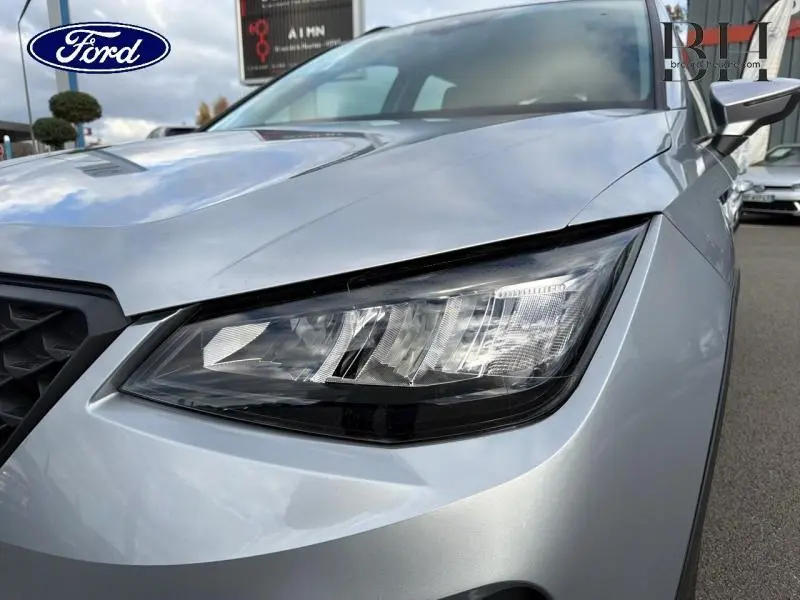 Gros plan sur le phare avant droit d'une SEAT ARONA gris urbain métal, soulignant son design moderne et anguleux.