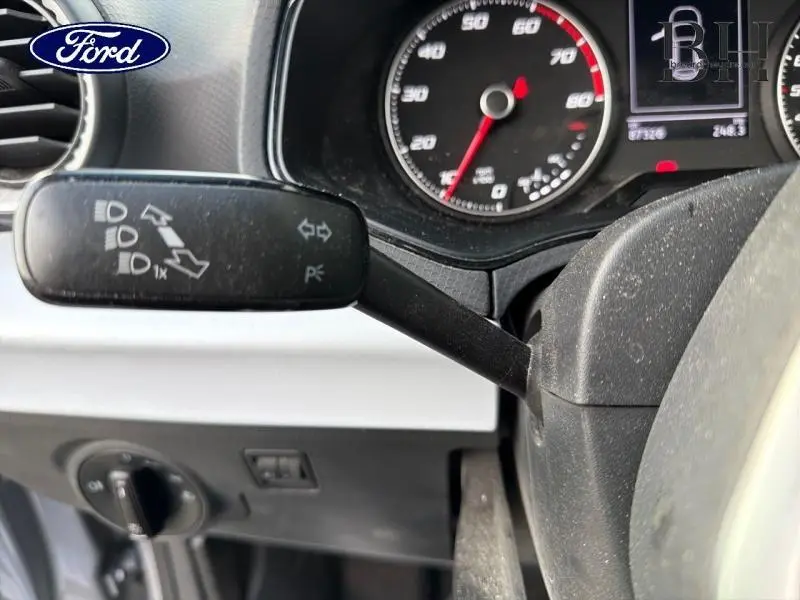 Gros plan sur la manette de clignotant à gauche du volant dans l'habitacle d'une SEAT Arona gris urbain.