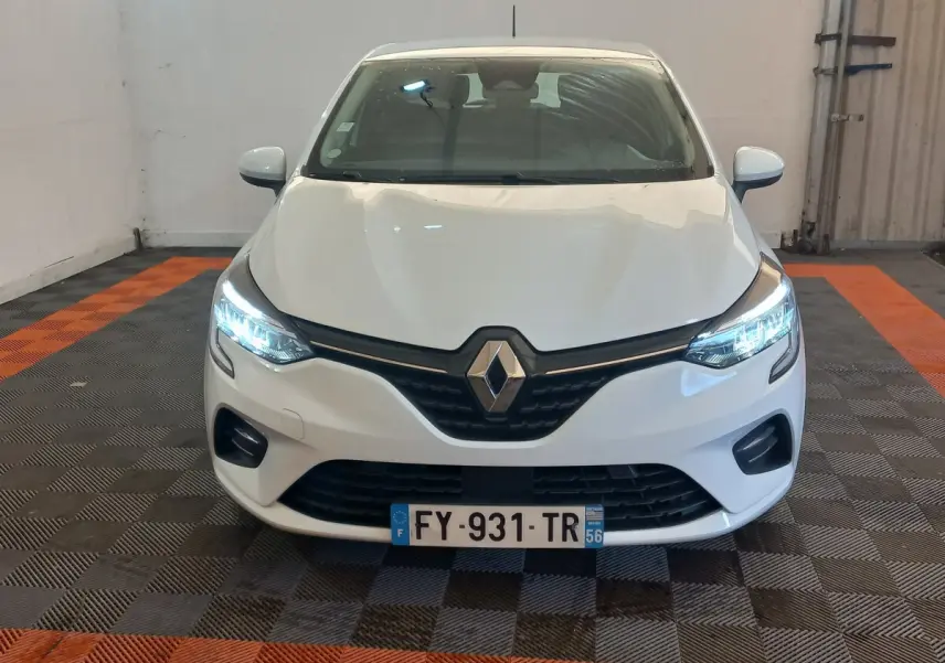 Vue frontale d'une Renault Clio Business blanche avec phares LED allumés dans un garage.