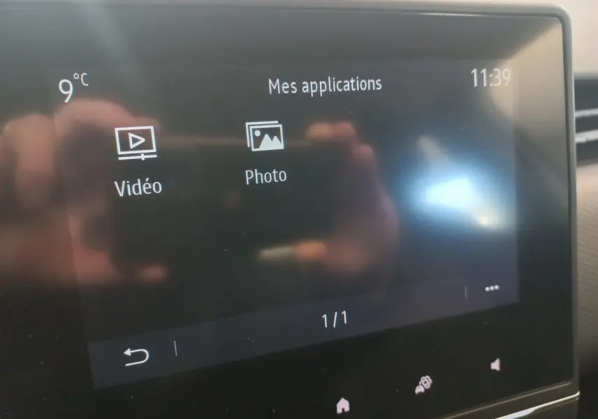 Écran tactile central de la Renault Clio Business blanc, affichant les applications vidéo et photo, température 9°C.