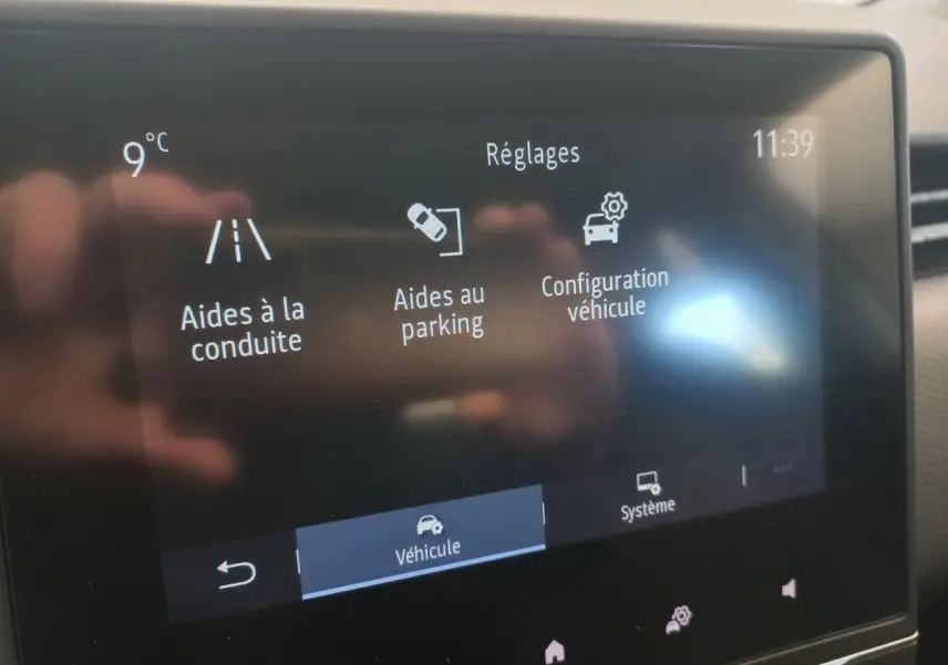 Écran tactile intérieur affichant les réglages d’aides à la conduite et parking dans une Renault Clio blanche.