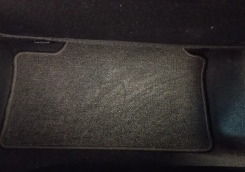 Tapis de sol noir en tissu dans l'habitacle d'une Renault Clio Business blanche, vue intérieure au sol côté passager.