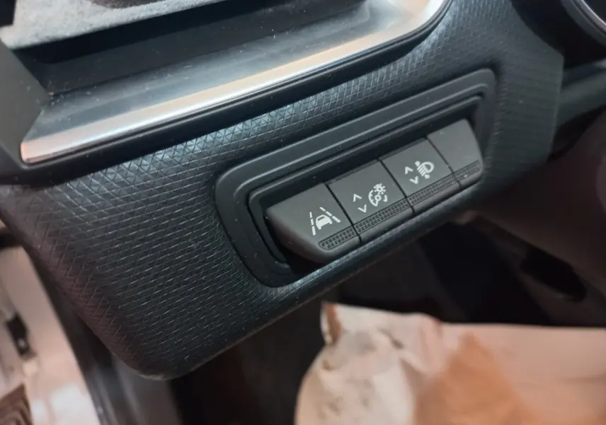 Gros plan sur les boutons de réglage d'assistance à la conduite dans l'habitacle noir de la Renault Clio Business blanche.