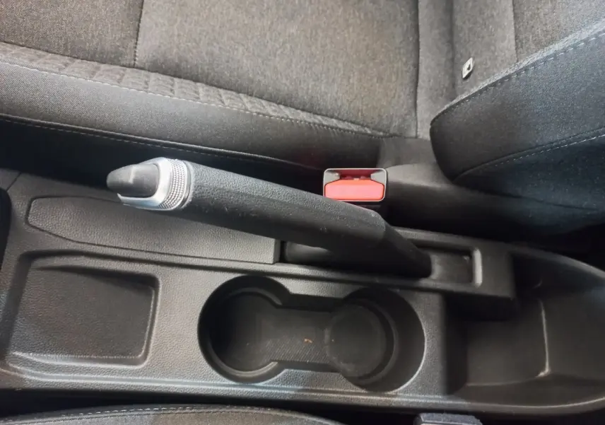 Vue rapprochée de la console centrale intérieure noire de la Renault Clio Business avec frein à main manuel et porte-gobelets.