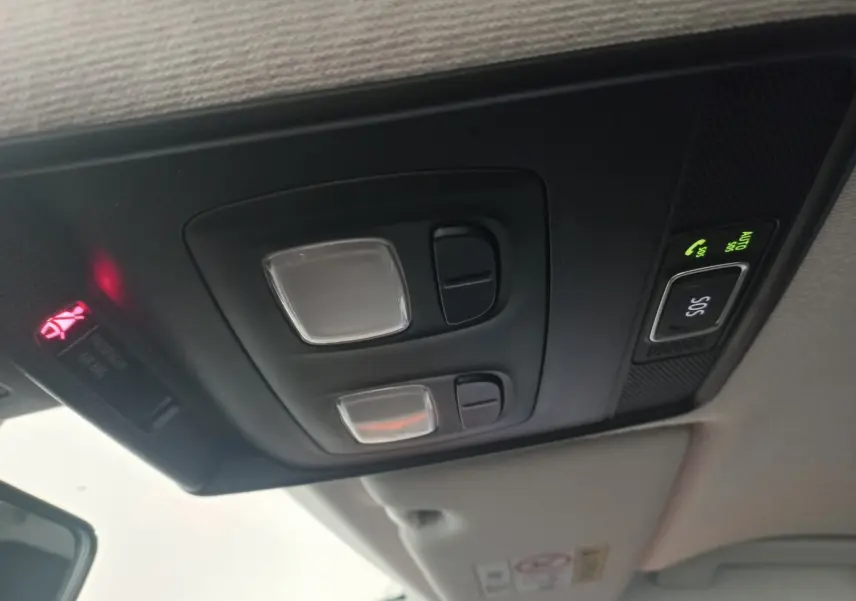 Plafonnier intérieur avec commandes d’éclairage et bouton SOS activé dans une Renault Clio blanche, vue vers l’avant.