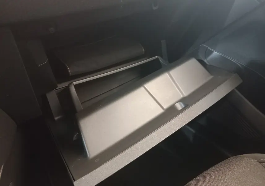 Gant de boîte à gants ouvert en plastique noir dans l'habitacle d'une Renault Clio Business blanche, vue côté passager.