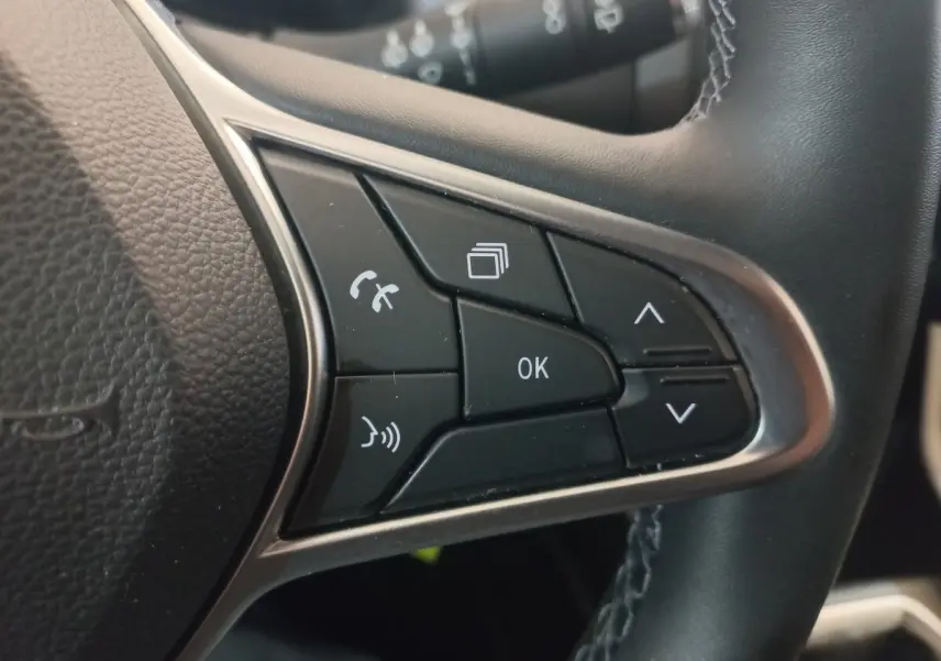 Gros plan sur les commandes multifonctions du volant cuir synthétique de la Renault Clio Business blanche, version 2021.