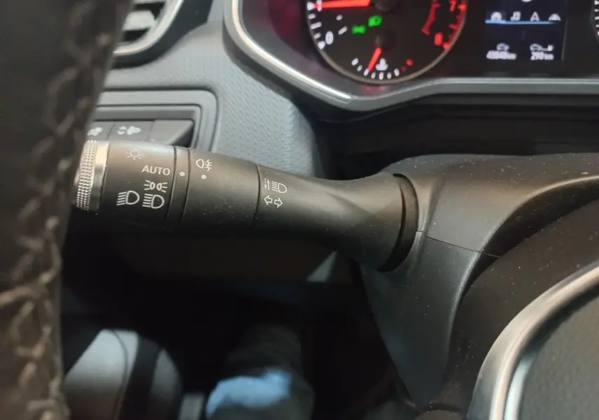 Gros plan sur la commande des phares et clignotants à gauche du volant dans le tableau de bord d'une Renault Clio blanche 2021.