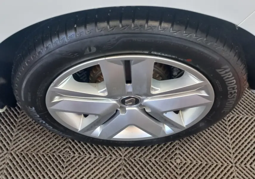 Gros plan sur la roue avant droite de la Renault Clio Business blanche, avec jante alliage et pneu Bridgestone.