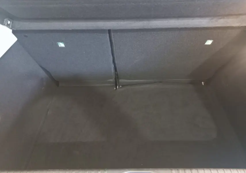 Vue intérieure du coffre spacieux et vide de la Renault Clio Business blanche, version 2021, avec banquette arrière rabattue.