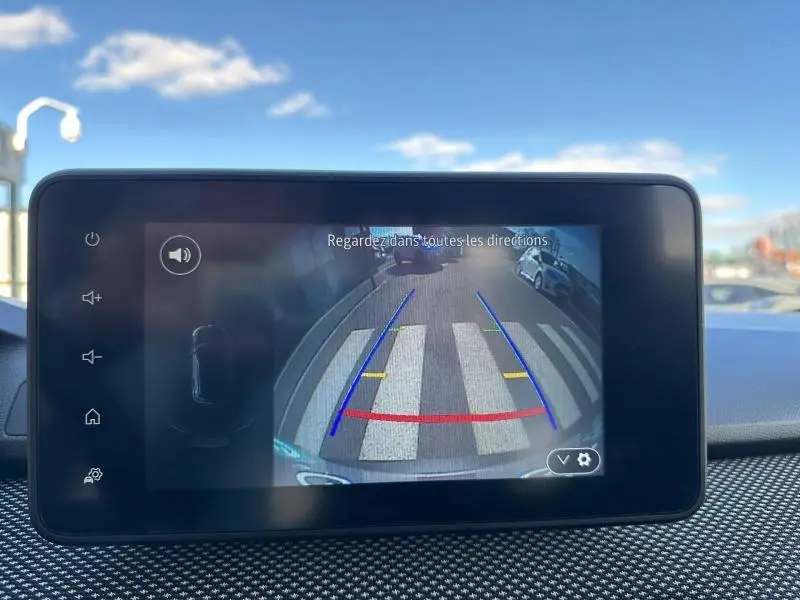 Écran de caméra de recul du Dacia Jogger 2025, montrant la vue arrière avec marquage au sol et véhicules stationnés.