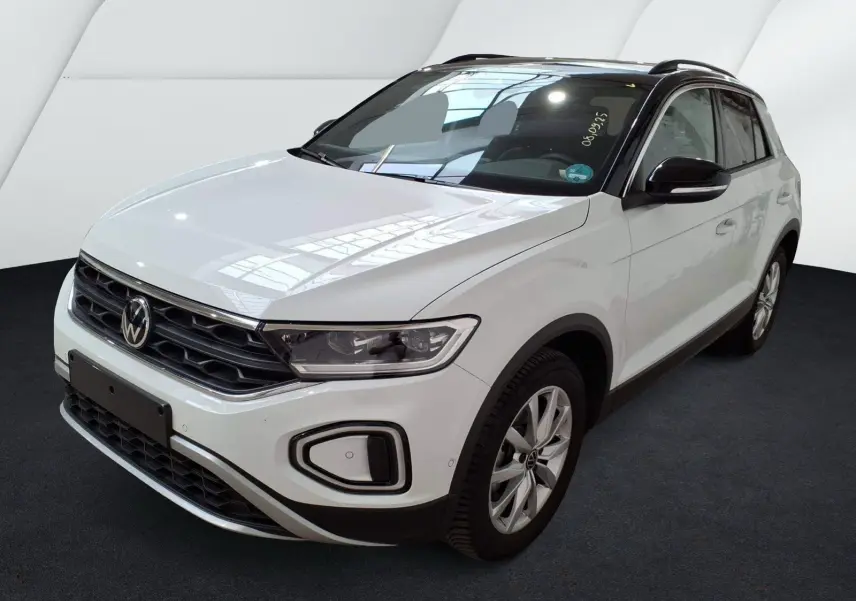 Volkswagen T-Roc blanc en 3/4 avant droit, avec toit noir et jantes alliage, sur fond neutre intérieur.