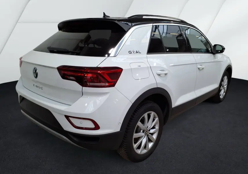 Volkswagen T-Roc blanc en 3/4 arrière droit, toit noir et badge Goal sur le montant arrière.