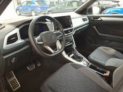 Vue intérieure côté conducteur du Volkswagen T-Roc blanc 2025, mettant en valeur le volant multifonction et la console centrale moderne.