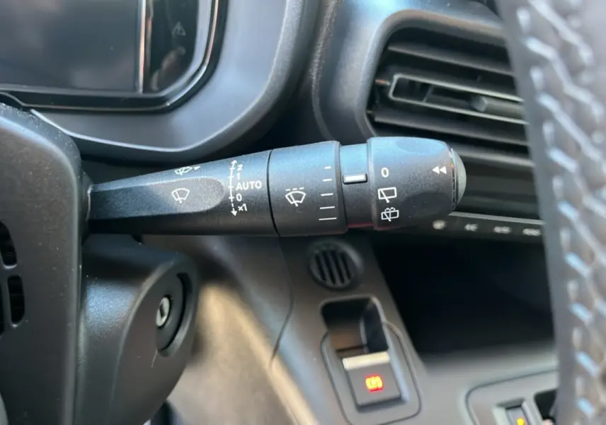 Gros plan sur la commande des essuie-glaces à gauche du volant cuir dans l’habitacle du Citroën Berlingo gris 2025.