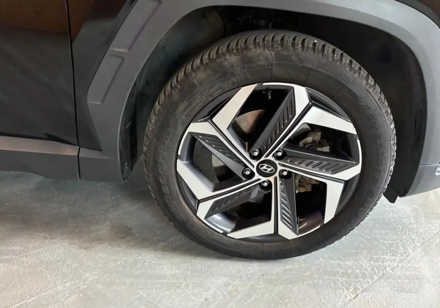 Gros plan sur la roue avant gauche noire d’un Hyundai Tucson 2022, mettant en valeur la jante alliage au design moderne.
