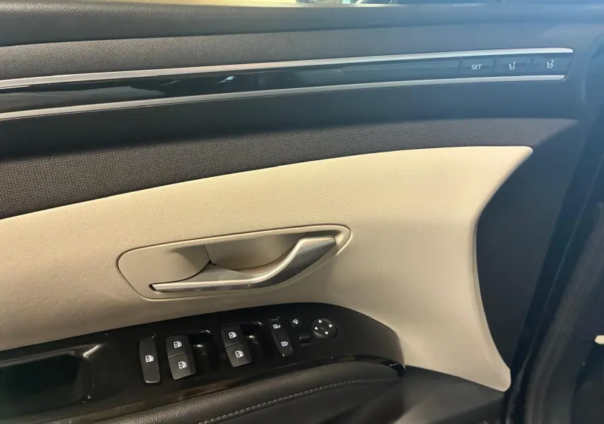 Détail de la porte avant gauche du Hyundai Tucson noir 2022, avec commandes électriques et garniture beige et noire.