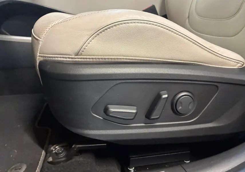 Gros plan sur les commandes électriques du siège beige côté conducteur du Hyundai Tucson 2022 hybride.