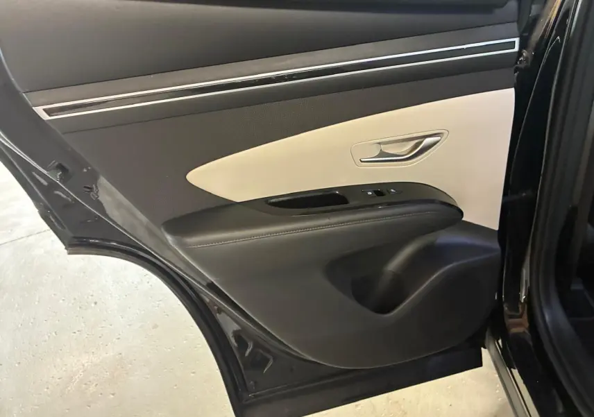 Vue rapprochée de la porte arrière gauche noire du Hyundai Tucson 2022 avec garniture intérieure bicolore beige et noire.