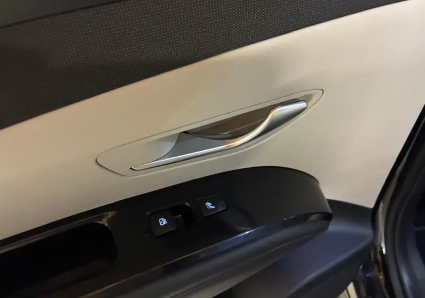 Gros plan sur la poignée intérieure et les commandes de porte côté gauche du Hyundai Tucson noir, finition Executive 2022.