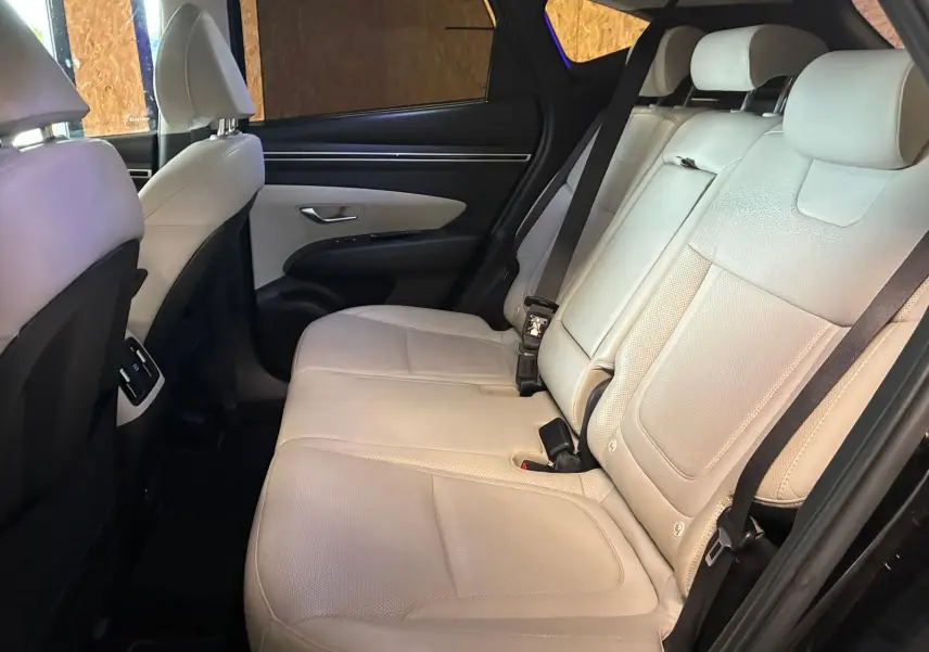 Vue intérieure côté gauche des sièges arrière en cuir beige du Hyundai Tucson noir 2022, avec ceinture de sécurité visible.