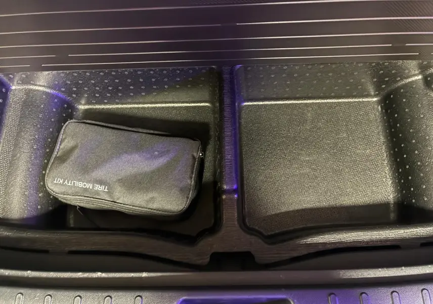 Gros plan sur le rangement sous le coffre du Hyundai Tucson noir 2022, avec trousse de mobilité noire visible.