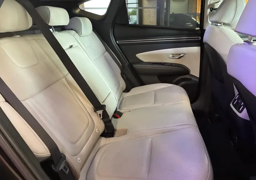 Vue intérieure côté droit des sièges arrière en cuir beige du Hyundai Tucson 2022, avec ceintures de sécurité visibles.