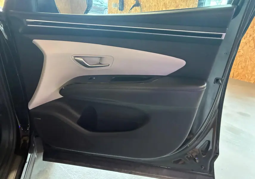 Vue intérieure de la porte avant droite noire du Hyundai Tucson 2022 avec insert clair et poignée argentée.