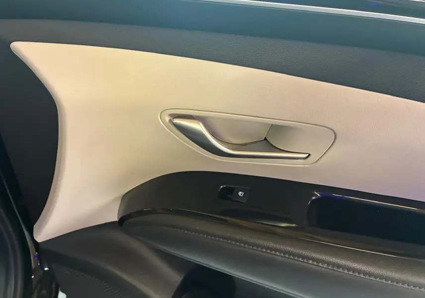 Gros plan sur la poignée intérieure et le panneau de porte beige et noir du Hyundai Tucson 2022 hybride.