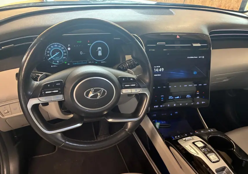 Vue intérieure centrée sur le volant noir et le tableau de bord numérique du Hyundai Tucson hybride 2022, avec écran tactile vertical.