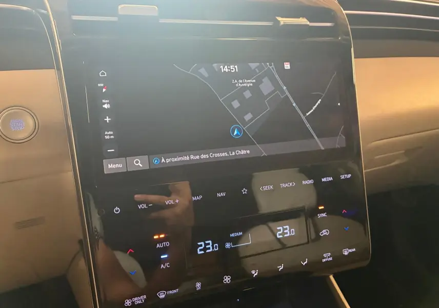 Vue rapprochée de la console centrale du Hyundai Tucson 2022 noire, affichant l'écran tactile du GPS et les commandes climatisation.