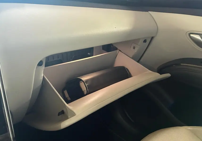 Vue intérieure côté passager du Hyundai Tucson 2022 hybride, boîte auto, avec boîte à gants ouverte et pochette noire visible.