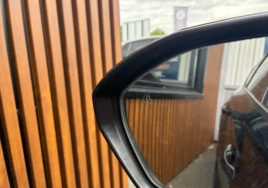 Rétroviseur côté droit du Hyundai Tucson noir 2022, reflétant la carrosserie et un mur en bois vertical.