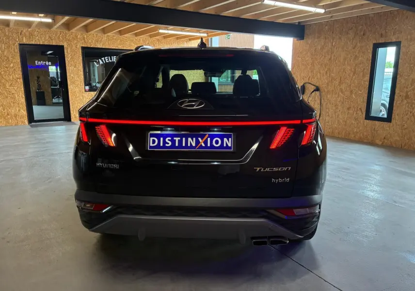 Vue arrière d'un Hyundai Tucson noir hybride 2022 avec feux arrière LED allumés dans un garage.