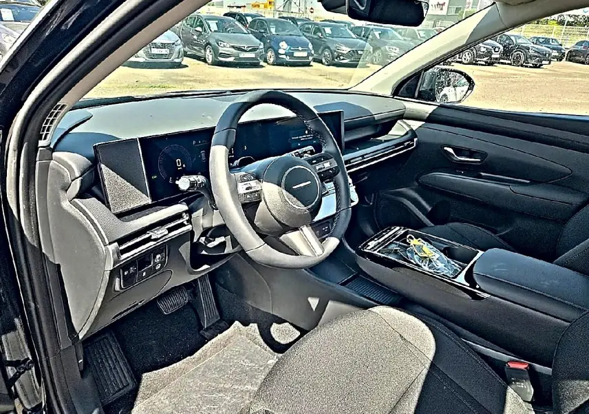 Vue intérieure côté conducteur du Hyundai Tucson noir 2026, mettant en valeur le tableau de bord digital et le volant multifonction cuir.