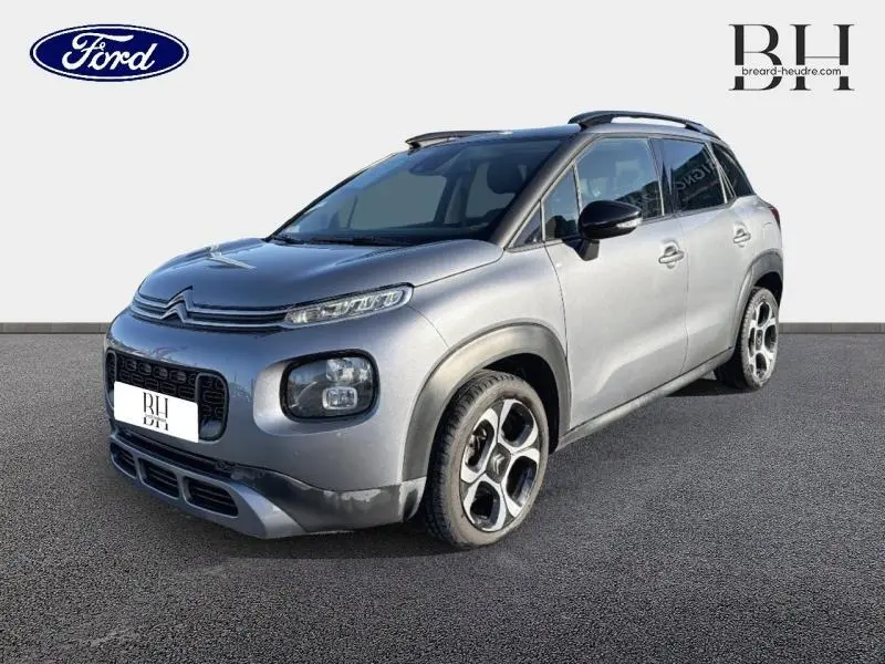 Citroën C3 Aircross gris acier vue 3/4 avant droit avec barres de toit et jantes diamantées noires et argentées.