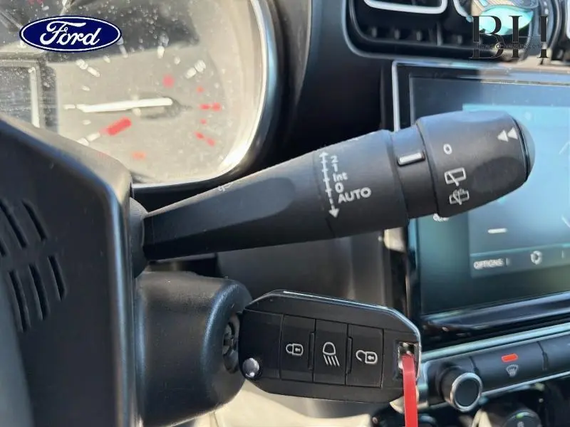 Gros plan sur la commande d'essuie-glace et clé de contact dans l'habitacle d'une Citroën C3 Aircross gris acier.