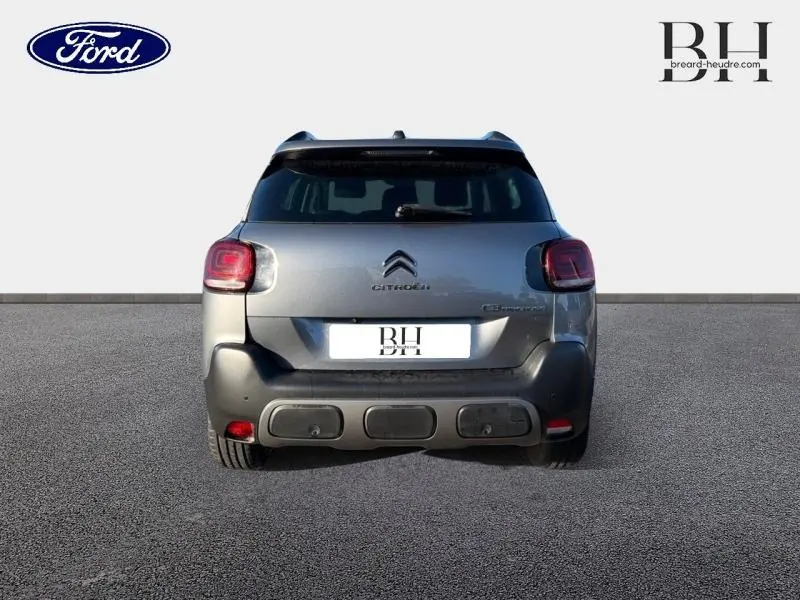 Vue arrière d'une Citroën C3 Aircross gris acier avec barres de toit et feux arrière distinctifs à LED.