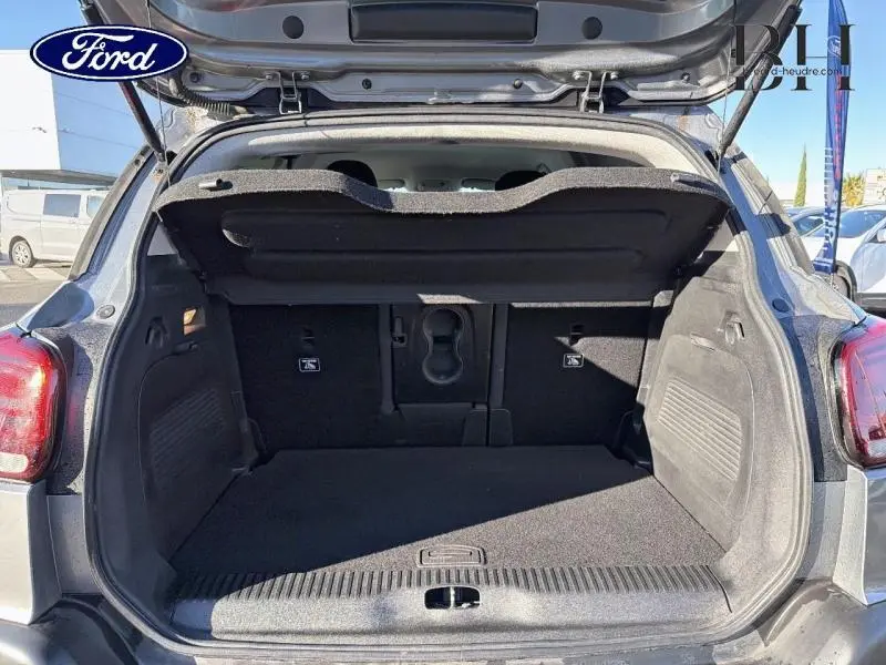 Coffre ouvert vu de l'arrière d'un Citroën C3 Aircross gris acier, montrant l'espace de chargement et la tablette cache-bagages.