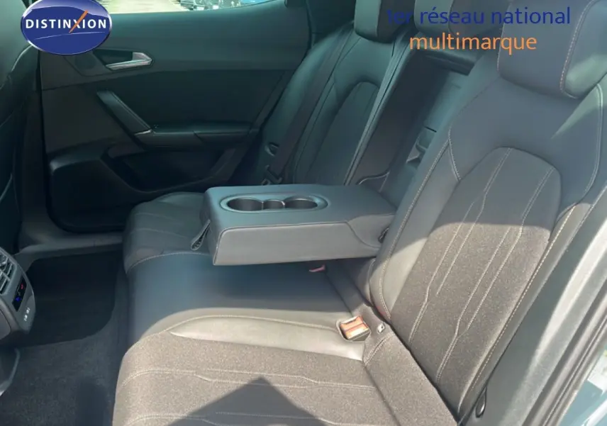 Vue intérieure des sièges arrière du CUPRA Formentor 1.5 eTSI en tissu noir avec accoudoir central et porte-gobelets.