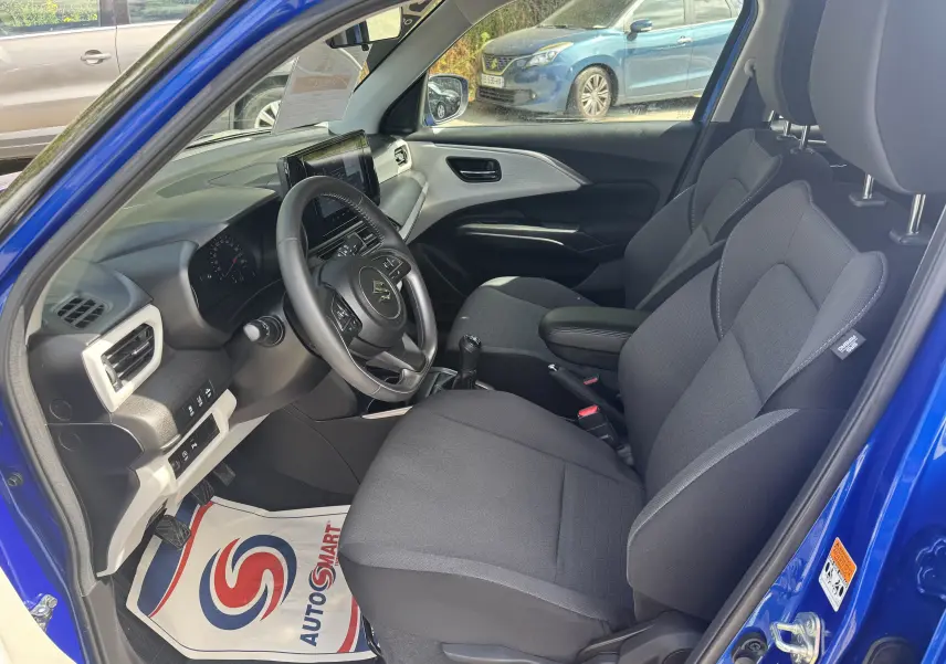 Intérieur avant droit de la Suzuki Swift 1.2 Pack Hybrid 2024 bleu, montrant sièges tissu noirs et tableau de bord moderne.