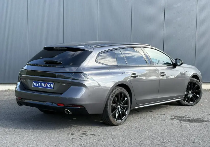 Peugeot 508 SW gris Platinium vue 3/4 arrière droit avec jantes noires et vitres surteintées.