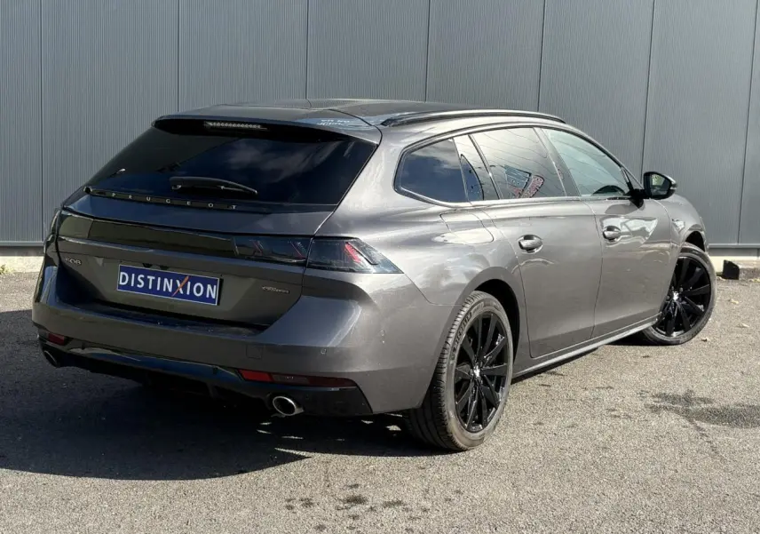 Peugeot 508 SW gris Platinium vue 3/4 arrière droit avec jantes noires et vitres surteintées.