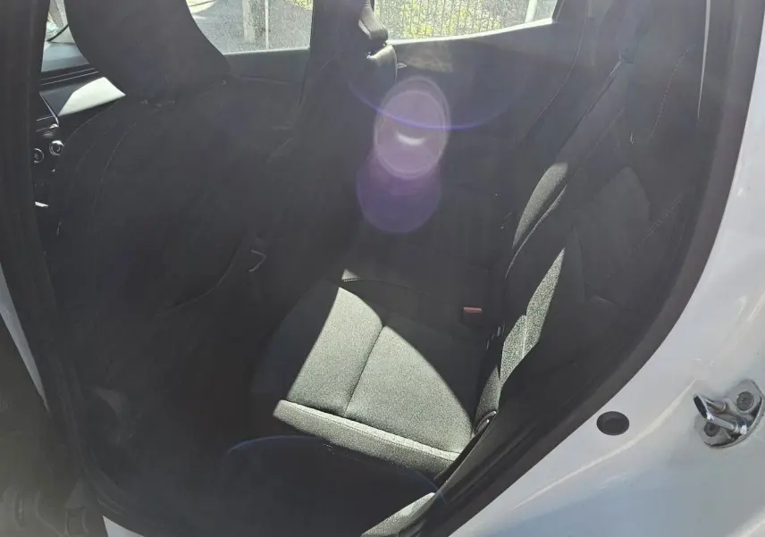 Vue intérieure côté arrière droit de la Renault Clio blanche glacier 2021, sièges arrière en tissu noir et ouvertures de porte visibles.