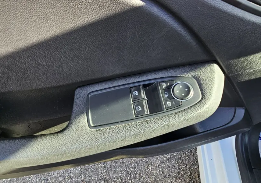 Gros plan sur la commande des vitres électriques côté conducteur de la Renault Clio blanc glacier 2021.
