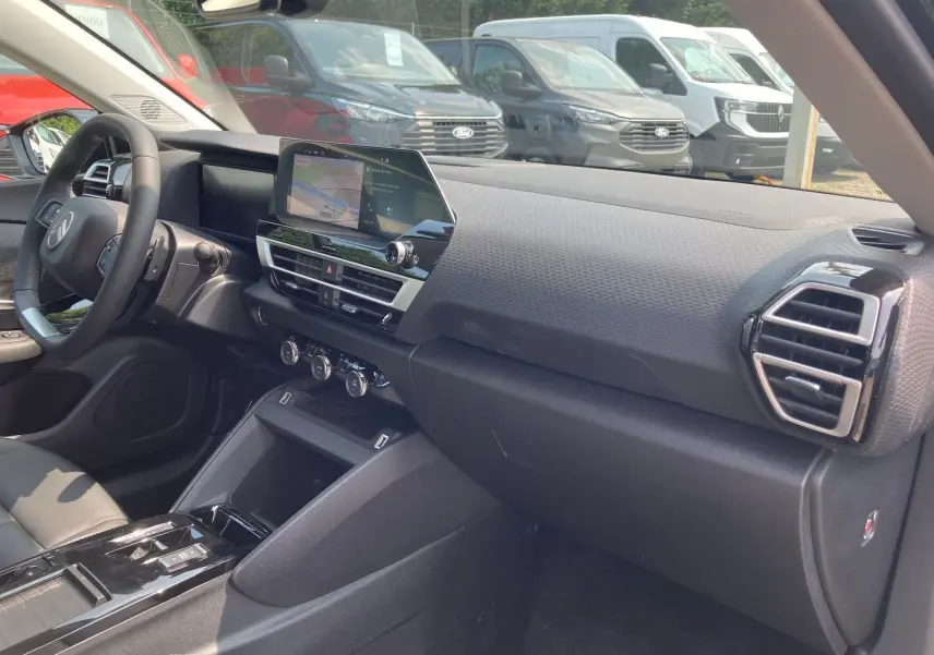 Vue intérieure côté passager du tableau de bord et console centrale du Citroën C4 Facelift Hybrid 2025 en noir Perla.