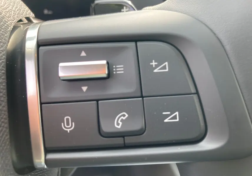Gros plan sur les commandes au volant du Citroën C4 noir Perla, boutons de volume et téléphone visibles.